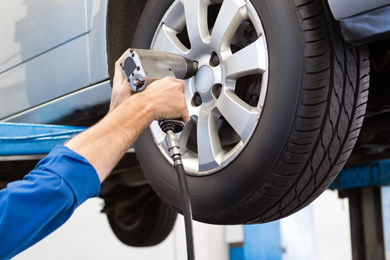 Mechanic fitting a tyre and wheel using an impact wrench